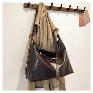 Dettaglio di borsa tote lucida color cioccolato con spalline sottili su gancio di legno