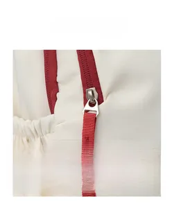 Detail view of cream canvas backpack featuring red zipper edges and silver metal pullers