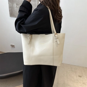 Detailed close-up of cream white tote bag with elegant golden buckles and long shoulder strap