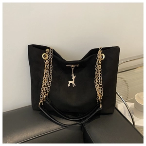 Détail d'un sac cabas en daim noir avec pendentif cerf doré et bandoulière chaîne