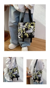 Detail view of large Oxford fabric tote bag featuring yellow graffiti print and buckle closure