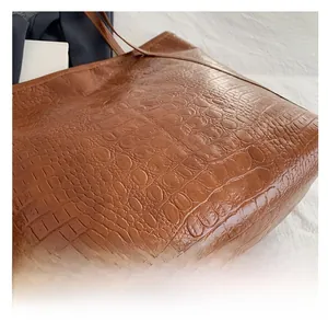 Macro shot of high-gloss brown faux crocodile texture on a large tote handbag detail