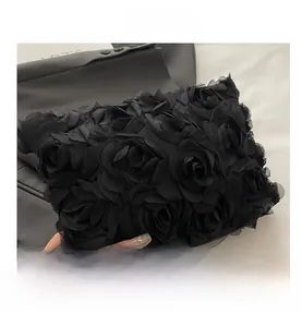 Close-up of black evening clutch bag with elegant 3D satin rose floral decorations