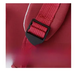 Close-up of durable black plastic buckle on dark red fabric travel backpack strap
