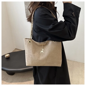 Détail du sac cabas en daim beige avec chaîne dorée et pendentif cerf sur mannequin
