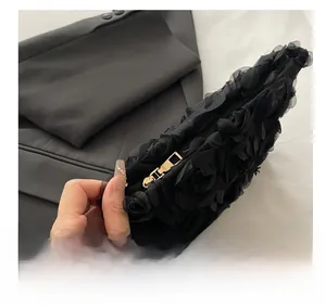 Close-up of smooth gold-tone zipper on black floral lace clutch bag with 3D texture