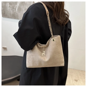 Détail du sac cabas beige en daim avec chaîne dorée et pendentif renne en métal