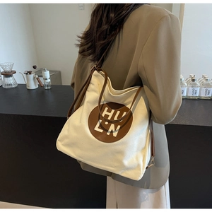 Detail of canvas tote bag with brown leather patch and adjustable shoulder straps