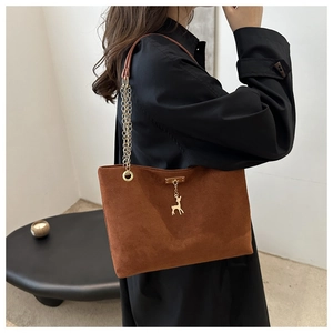 Vue détaillée du sac cabas en daim marron avec chaîne en métal et pendentif cerf doré