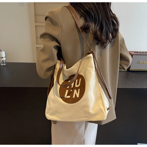 Detail view of large canvas tote bag with brown leather HU LN logo patch and long straps