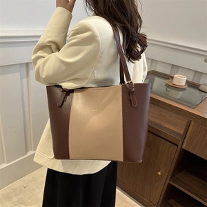 Detail of a large brown and beige contrast tote bag showing adjustable straps and PU leather