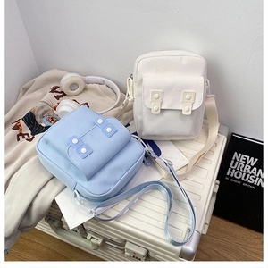 Detail of light blue and white canvas crossbody bags on luggage with headphones