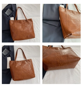 Detail view of brown crocodile embossed leather tote bag showing texture and stitching