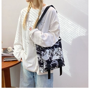 Close-up of black and white graffiti canvas messenger bag with durable plastic buckles