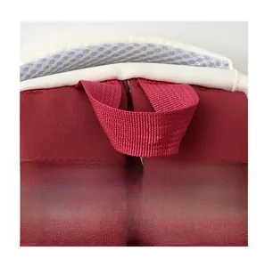 Detail of red travel backpack featuring a reinforced webbing handle and breathable mesh straps