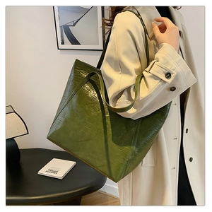 Detail showing the dark green crocodile embossed texture of the large tote bag