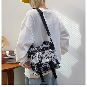 Detail of contrast graffiti print shoulder bag with adjustable strap on model