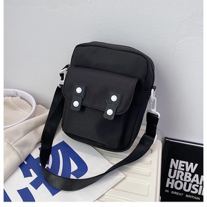 Close-up of black canvas crossbody bag with white buttons and wide shoulder strap detail