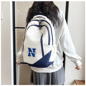Detail view of large white and navy school backpack on model showing back and straps