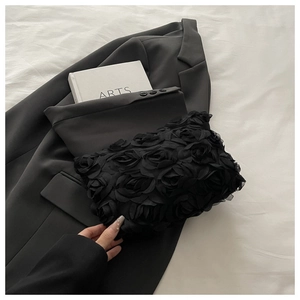 Detail of 3D fabric rose floral clutch bag on white bedding for evening fashion