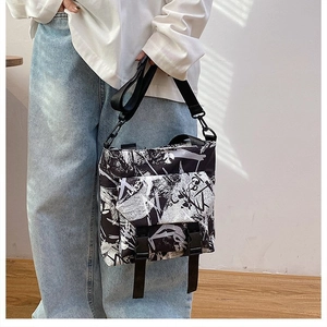 Close-up of black and white graffiti oxford bag featuring dual buckle closure detail