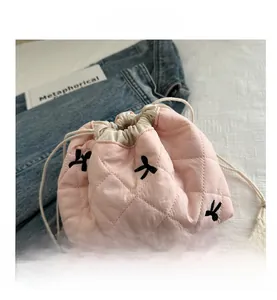 Detail of pink quilted bucket bag with drawstring closure and black knot embroidery