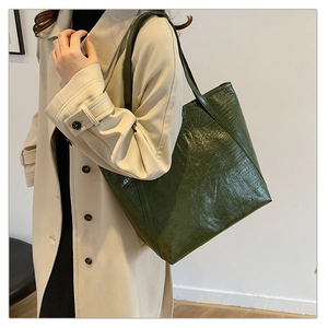 Detail shot of dark green tote bag featuring luxury crocodile pattern leather texture