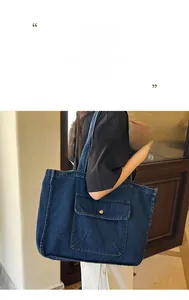 Detail of blue denim tote bag featuring a large front pocket and contrast white stitching