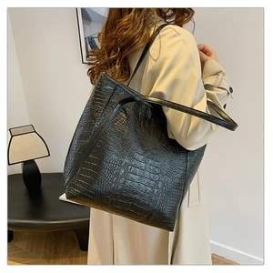 Black crocodile pattern tote bag shown on model in a modern minimalist setting