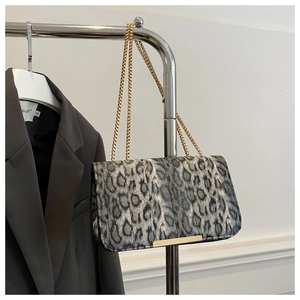 Détail d'un sac imprimé léopard avec chaîne dorée suspendu près d'un blazer gris