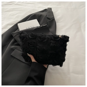 Close-up of 3D rose petal texture on a black evening clutch bag with gold zipper