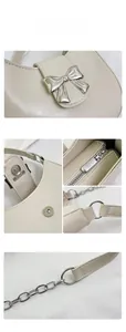 Close-up of cream white crescent bag showing silver metal bow and cracked texture leather