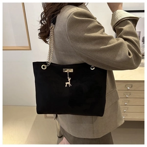 Détail du sac bandoulière en daim noir avec chaîne dorée et pendentif en métal en forme d'élan