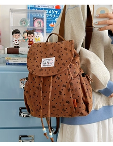 Detailed close-up of brown corduroy backpack with bow patterns and cute cartoon labels