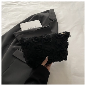 Detail of elegant black 3D lace rose clutch bag with a golden metal zipper closure