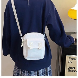 Detail of white canvas crossbody bag with double buckle flap pocket and adjustable strap