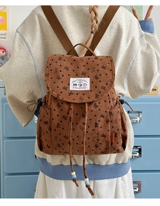 Detail of corduroy backpack with black heart and butterfly patterns on brown fabric