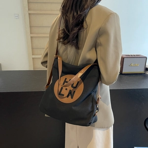 Minimalist black canvas tote bag with brown leather handles for women's daily commute