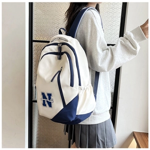 Side view of a large white canvas travel backpack with blue N embroidery and pockets