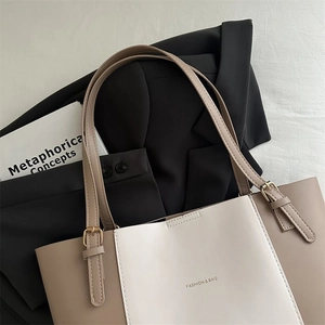 Detail of color-blocked tote bag with gold lettering on a stylish blazer background
