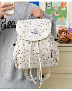 Detailed view of beige corduroy backpack with brown bow and heart patterns