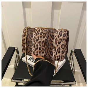Détail du sac léopard avec bandoulière à boules dorées sur un fond minimaliste