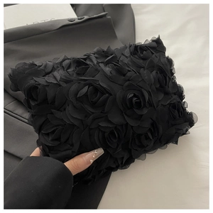 Detailed view of the black clutch bag featuring 3D fabric rose flower embellishments