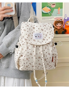 Detail of beige corduroy backpack featuring brown bow patterns and Happy Everyday patch