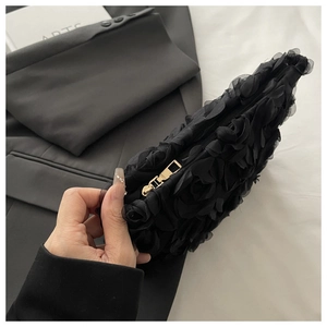 Detail of 3D rose texture and gold metal zipper on a black evening clutch bag