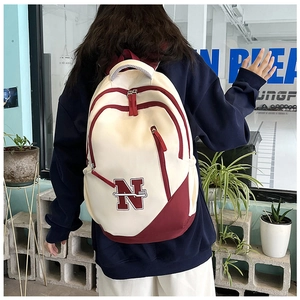 Detail view of large capacity backpack with red N logo and stylish patchwork on back