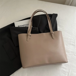 Detailed macro view of khaki tote bag showing gold metal buckle and leather straps