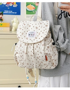 Detail of cream corduroy backpack featuring heart bow patterns and drawstring closure