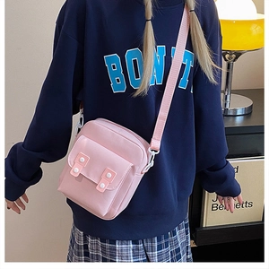Pink canvas crossbody bag detail showing adjustable strap and snap button pocket flap