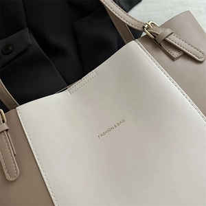 Close-up of beige leather tote bag stitching with Fashion & Bag logo and metal buckle